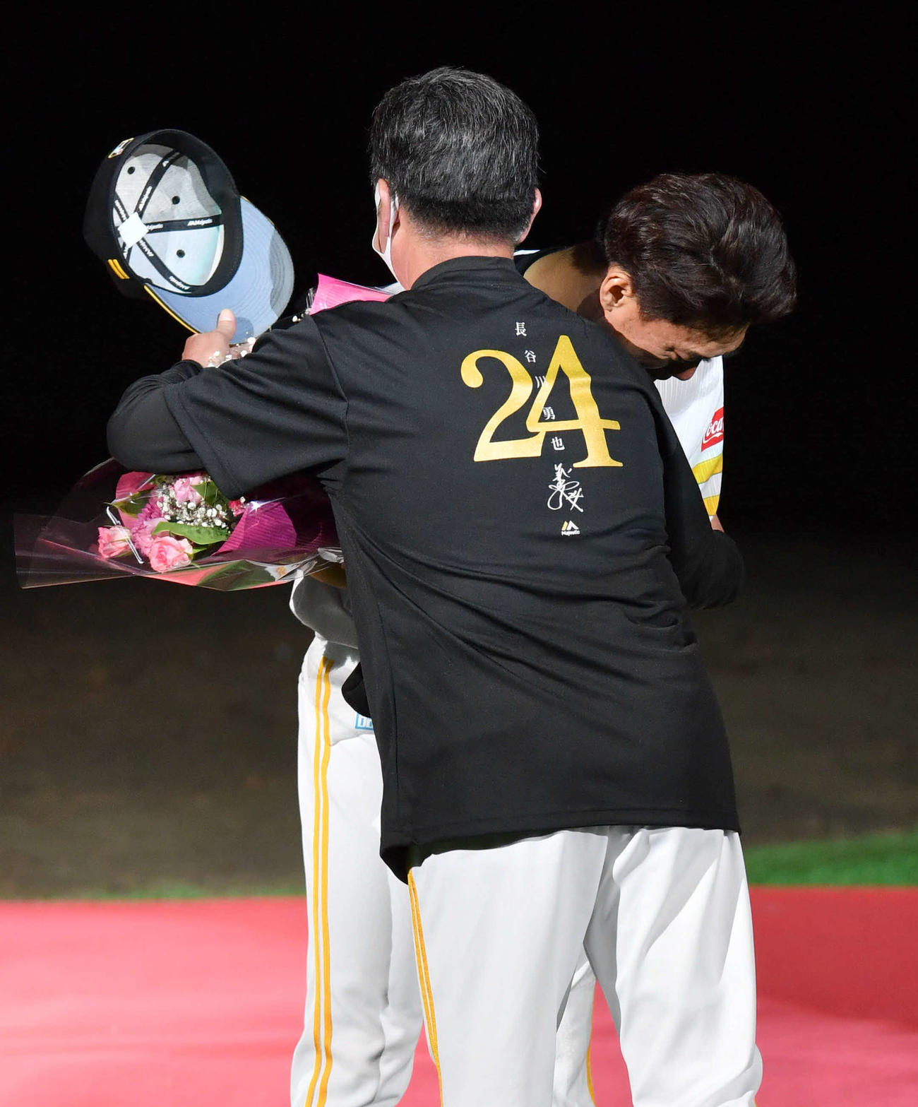 引退セレモニーで工藤監督（左）から花束を受け取り、抱き合う長谷川（撮影・岩下翔太）