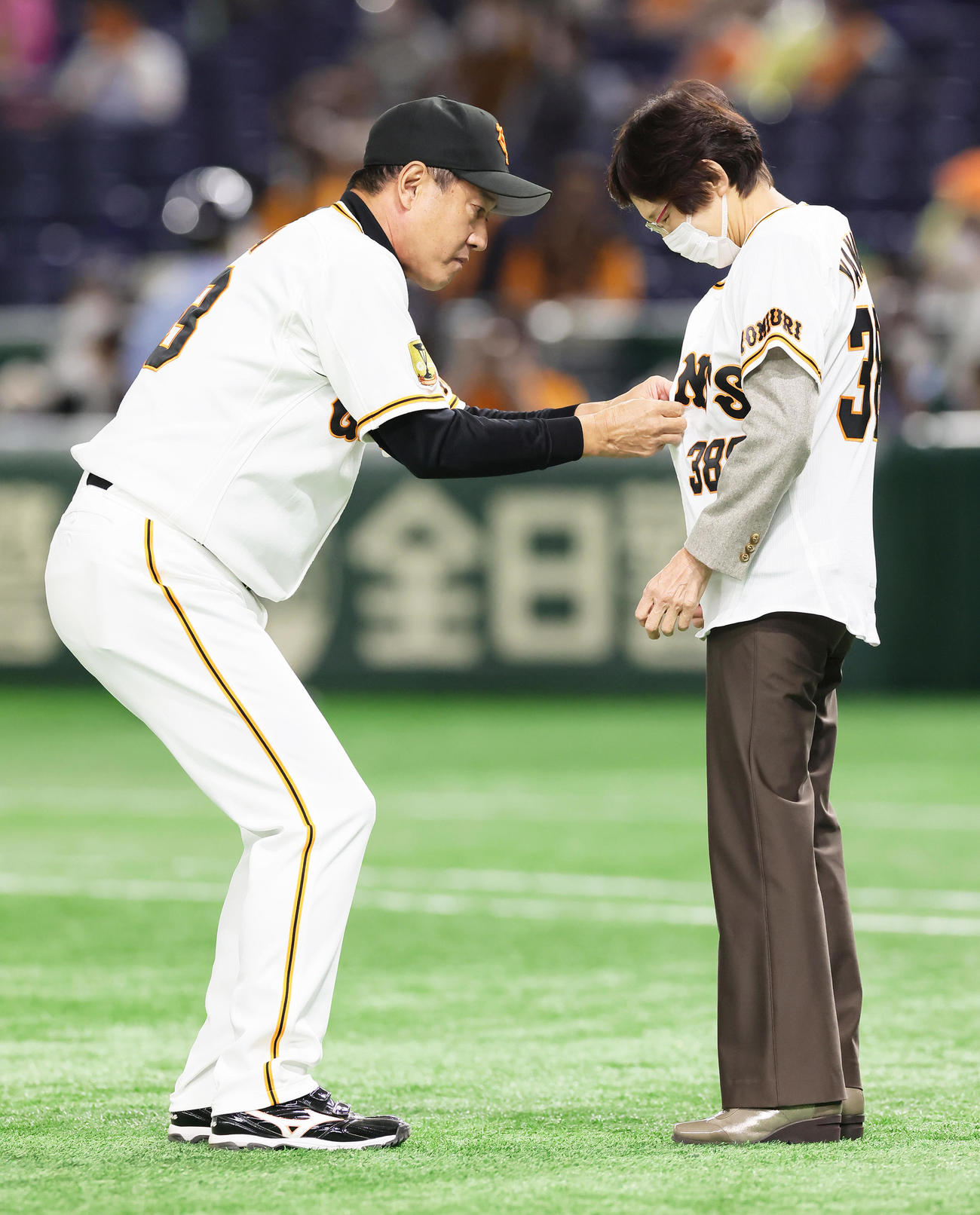 巨人対ヤクルト　長年勤めた場内アナウンスを終えた山中さん（右）は記念のユニホームを巨人原監督から着せてもらう（撮影・足立雅史）