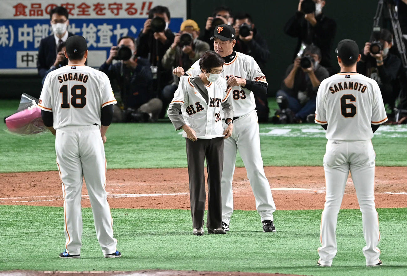 巨人対ヤクルト　場内アナウンスを引退する山中さん（左から2人目）は巨人原監督にユニホームを着せてもらう（撮影・山崎安昭）