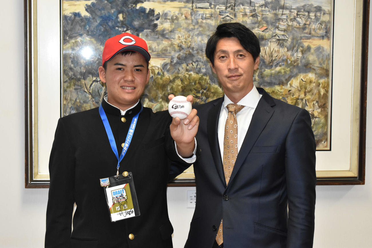 ボールを左手にポーズを決める広島育成1位の田辺の新家颯と鞘師スカウト（撮影・古財稜明）