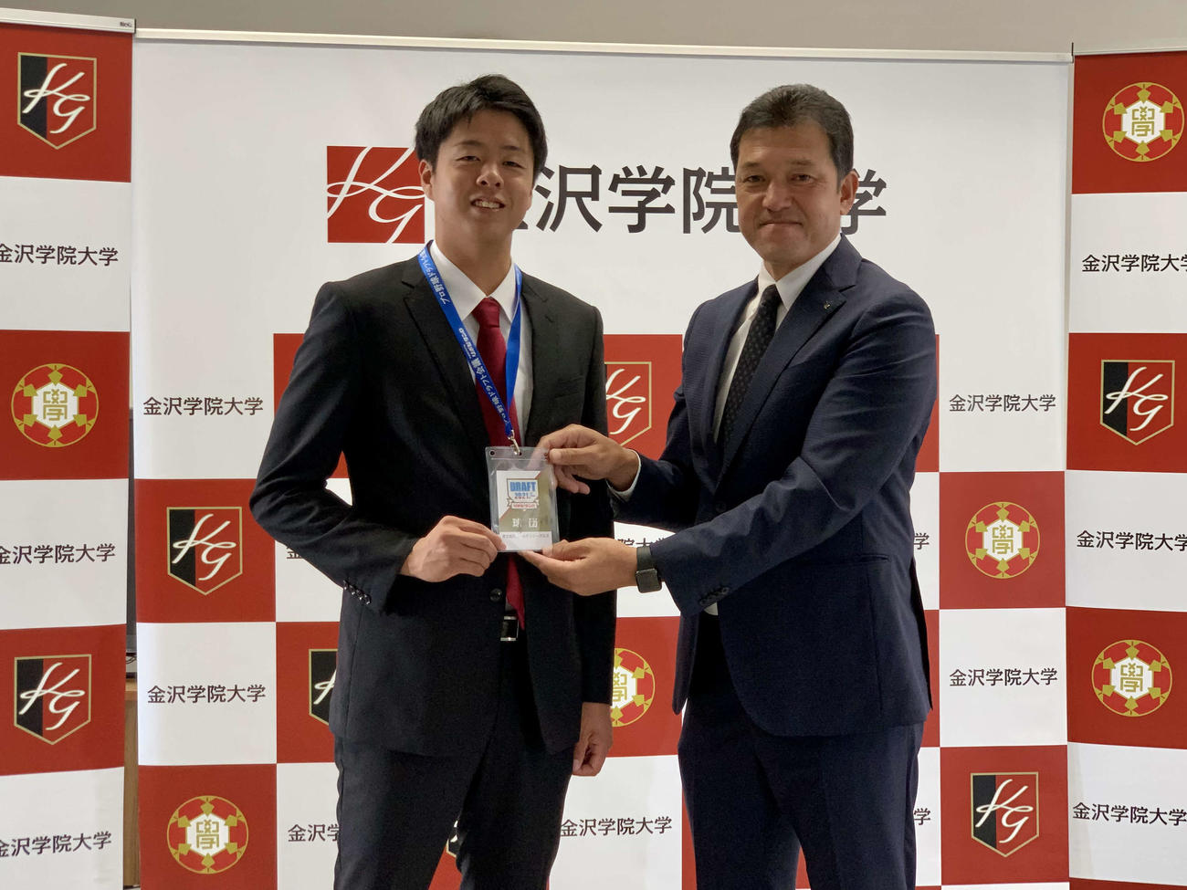 楽天ドラフト3位の金沢学院大・松井（左）は指名あいさつを終え、楽天山田スカウト（右）からドラフト会議で使用した関係者IDパスを受け取る（球団提供）