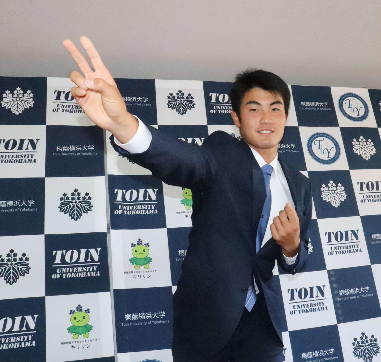 指名あいさつを受けた育成ドラフト6位の桐蔭横浜大・菊地は投球フォームを再現しながら笑顔を見せる（撮影・小早川宗一郎）