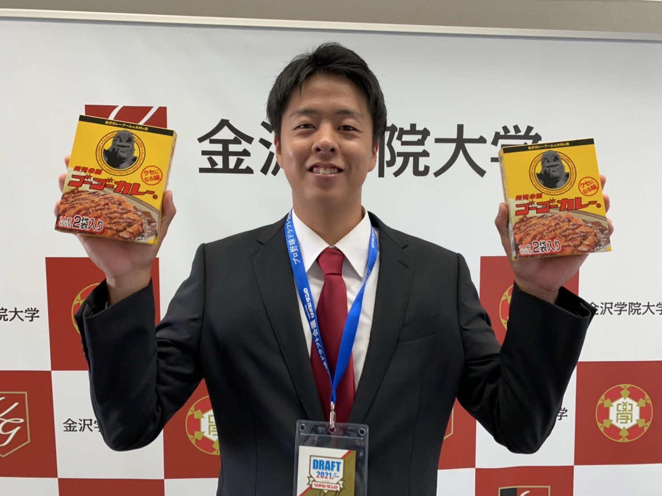 金沢名物のゴーゴーカレーを手に笑顔を見せる楽天ドラフト5位指名の金沢学院大・松井（球団提供）