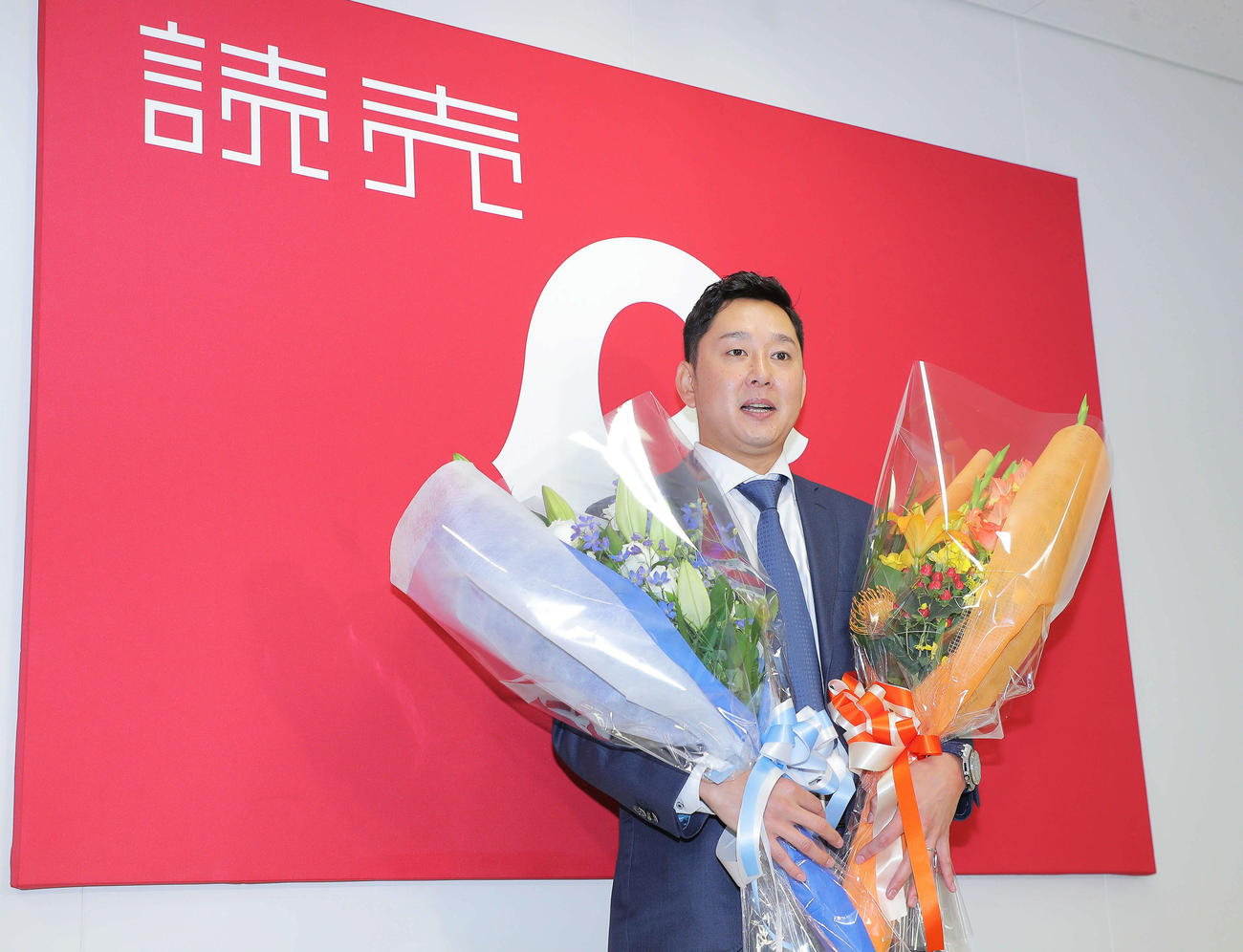 西武と巨人の色をイメージした花束を手に写真に納まる巨人野上（撮影・河田真司）