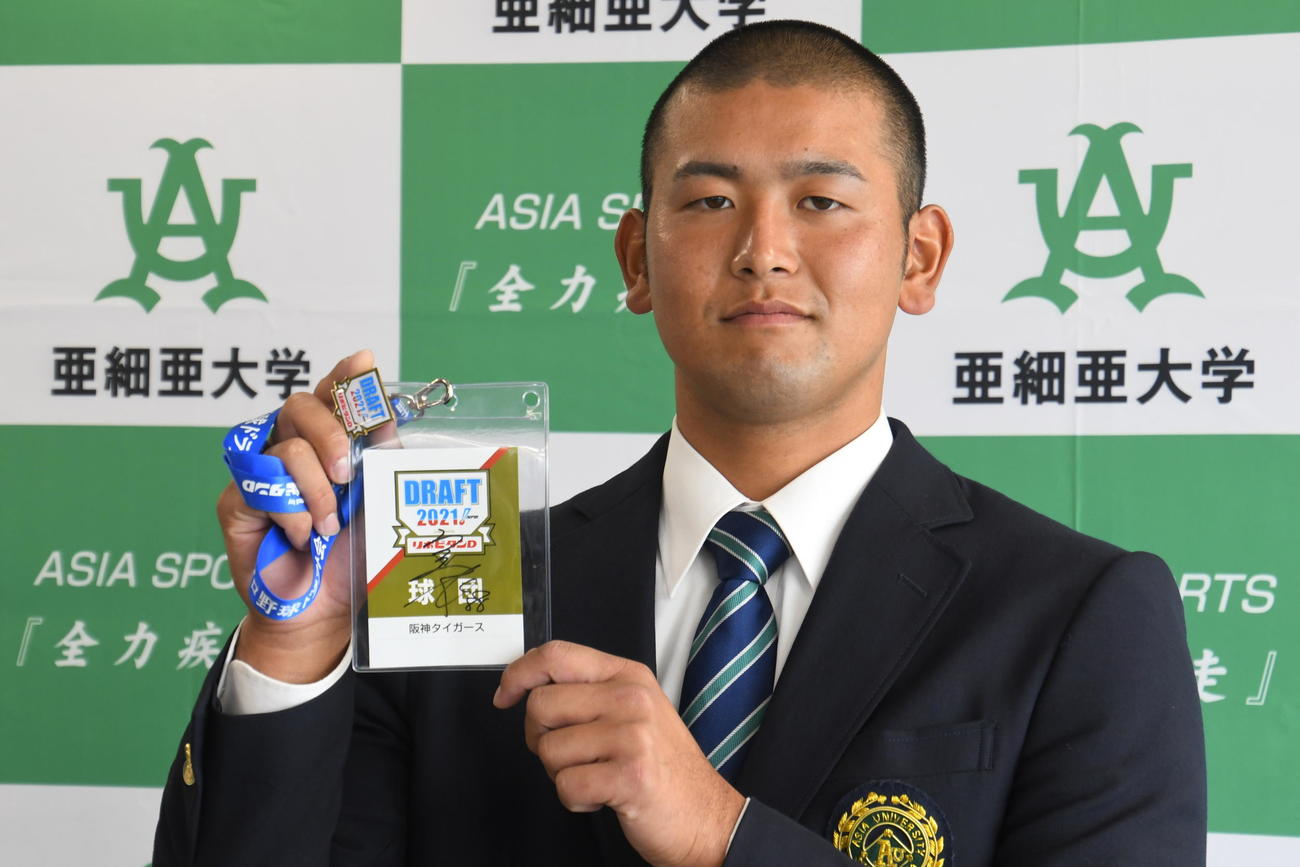 指名あいさつを終え、阪神矢野監督の直筆サインの入ったドラフトIDを手にする亜大・岡留（撮影・中野椋）