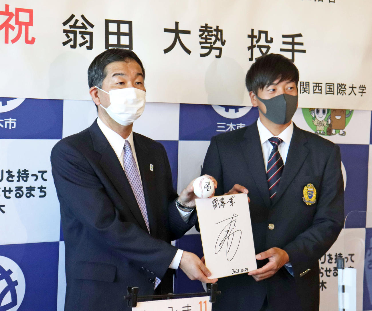 「開幕一軍」と記したサイン色紙を手にする巨人ドラフト1位の関西国際大・翁田（右）と仲田市長（撮影・小早川宗一郎）