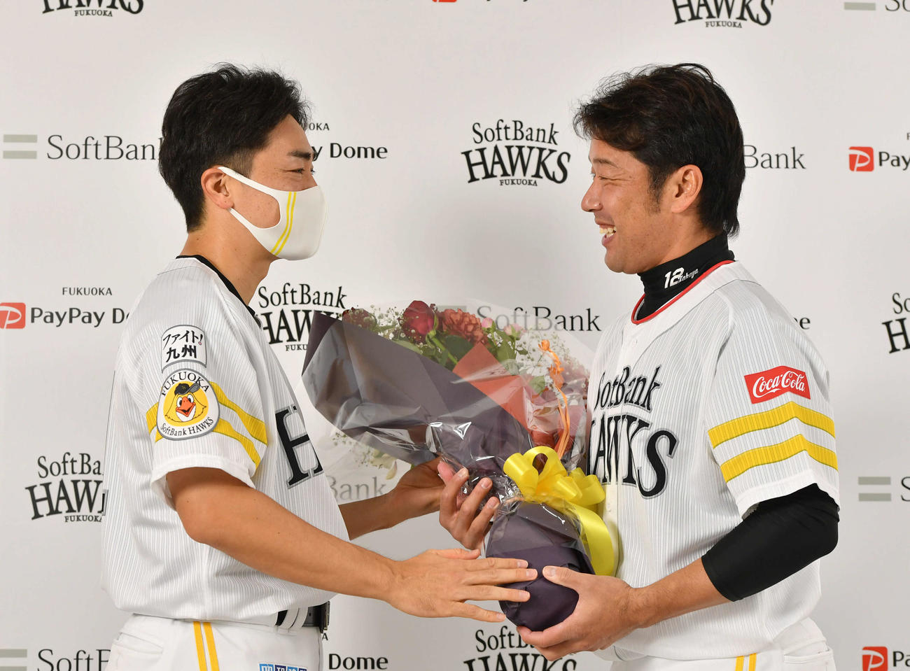 引退会見で和田（左）から花束を受け取り、笑顔で言葉を交わす高谷（撮影・岩下翔太）