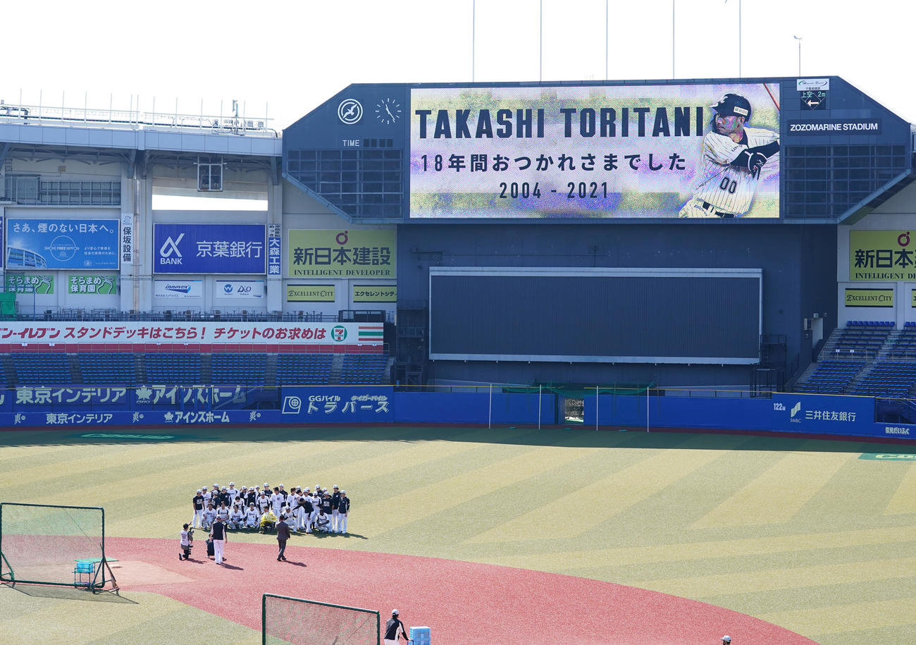 花束を手に記念写真に納まるロッテ鳥谷敬（前列中央）。電光掲示板には「18年間おつかれさまでした」とメッセージが映し出された（撮影・菅敏）