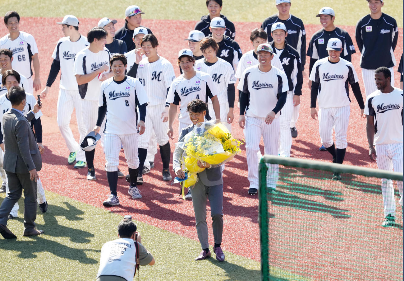 スーツ姿で引退のあいさつをしたロッテ鳥谷（手前）は、花束を手に笑顔でフィールドを後にする（撮影・菅敏）