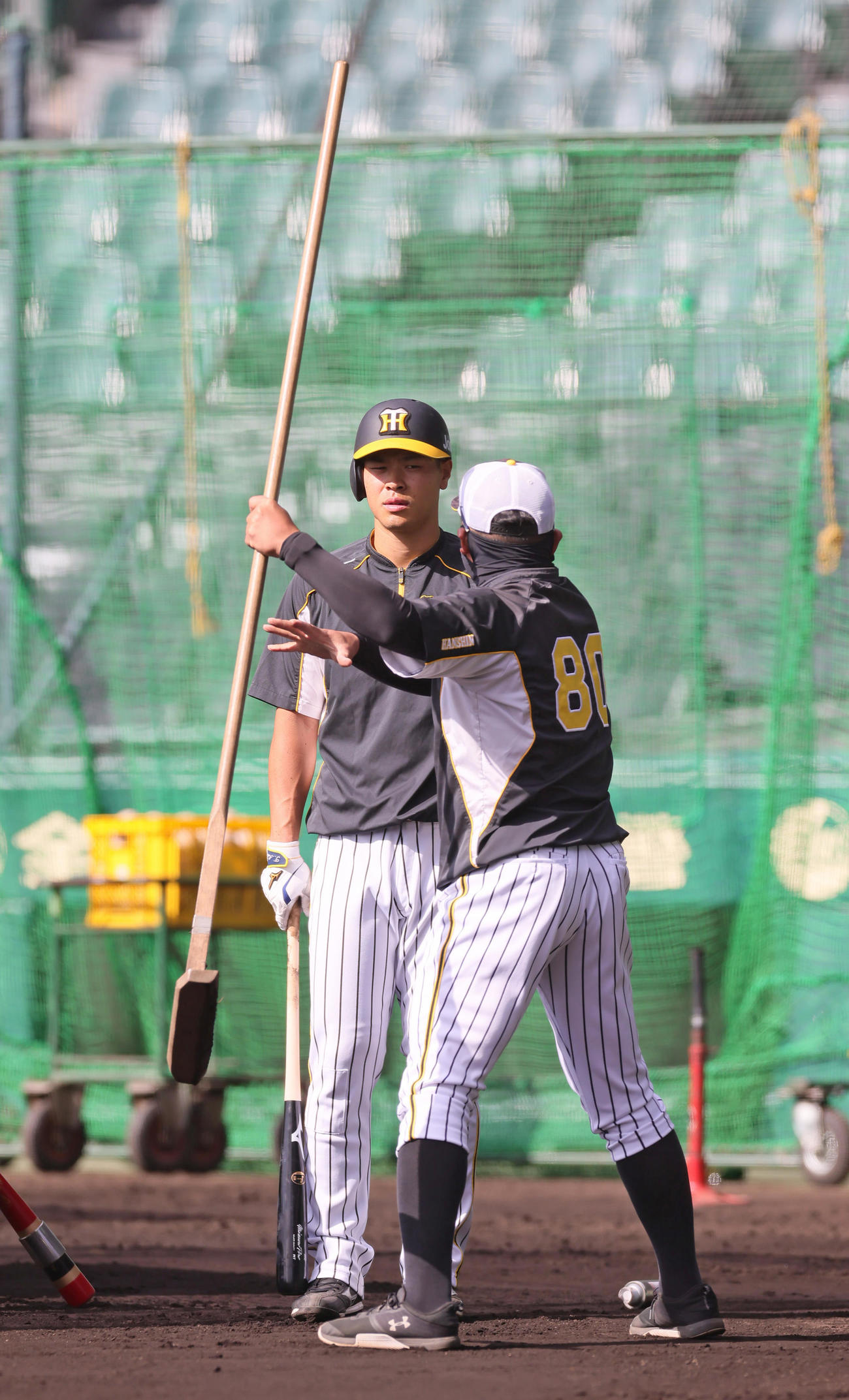 阪神佐藤輝（左）は北川コーチから指導を受ける（撮影・足立雅史）