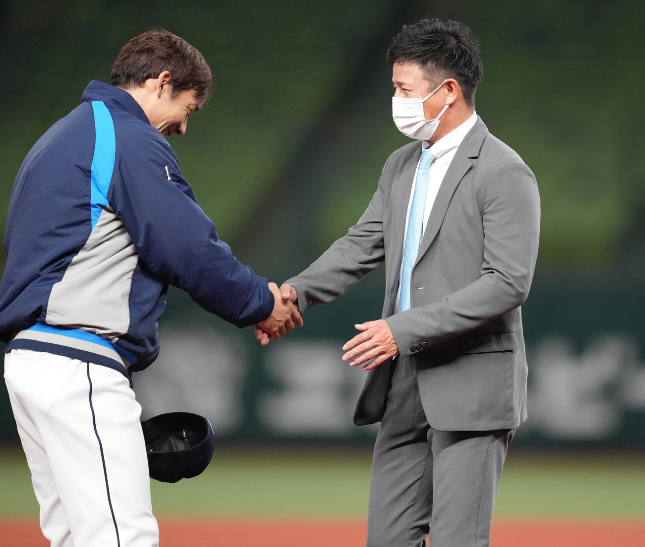 栗山（左）と握手する西武平石打撃コーチ（撮影・鈴木みどり）