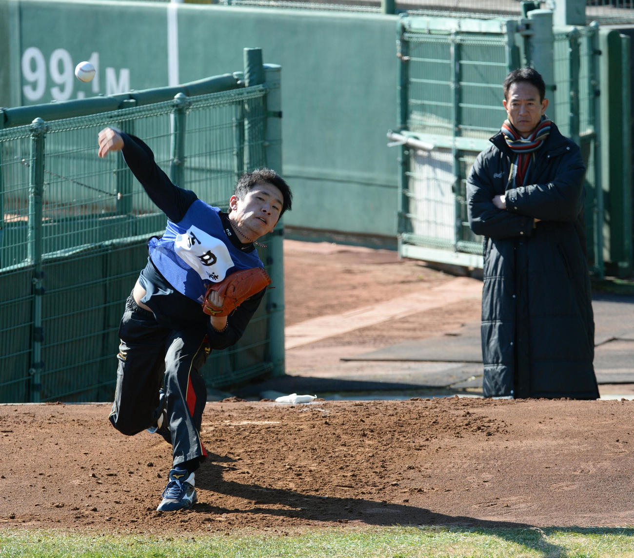ブルペンに入り投球練習する吉田凌を見守る酒井コーチ（後方）（2016年1月15日撮影）