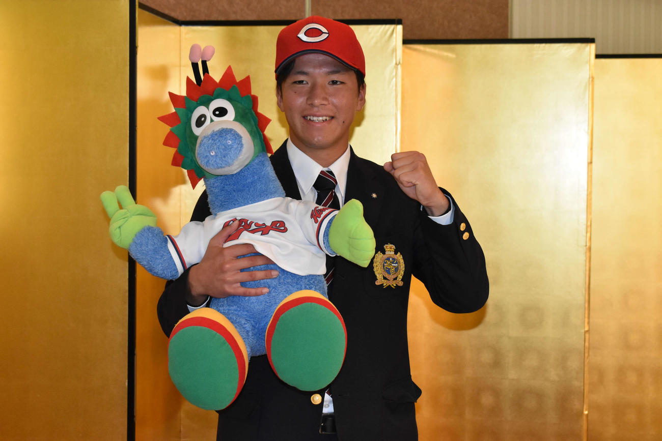 球団公式マスコットのスラィリーのぬいぐるみを抱き、ガッツポーズを決める広島ドラフト1位の関学大・黒原（撮影・古財稜明）
