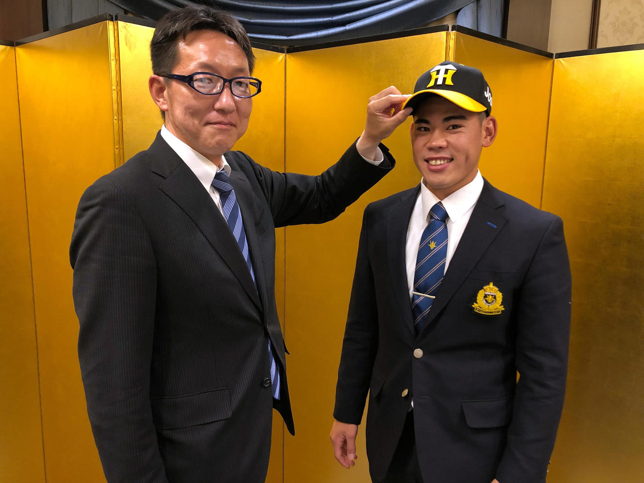 仮契約を行い笑顔をみせる阪神ドラフト2位の創価大・鈴木、左は吉野スカウト（球団提供）
