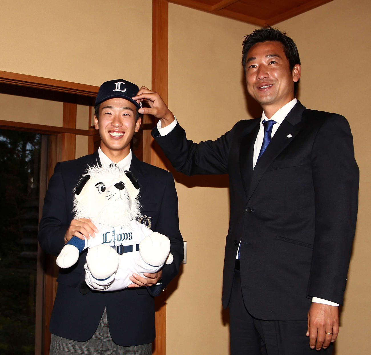西武鈴木敬洋・育成アマチュア担当（右）から帽子をかぶらせてもらい笑顔の滝沢