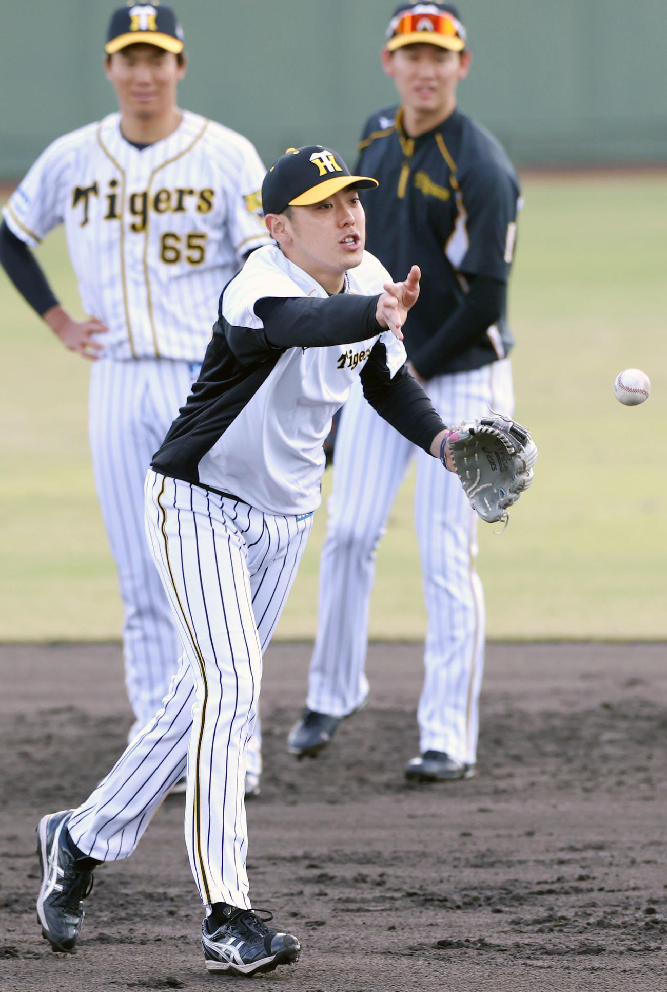 小川（手前）は内野ノックでトスする。左は湯浅、右は及川（撮影・上山淳一）