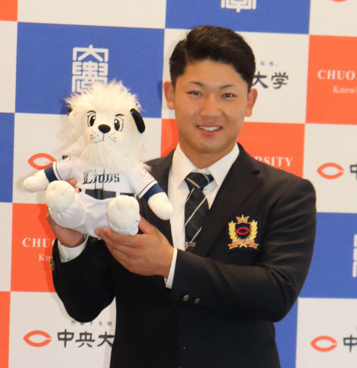 西武3位指名の中大・古賀は指名あいさつを終え、球団マスコットのレオのぬいぐるみを持ち笑顔を見せる（2021年10月18日撮影）