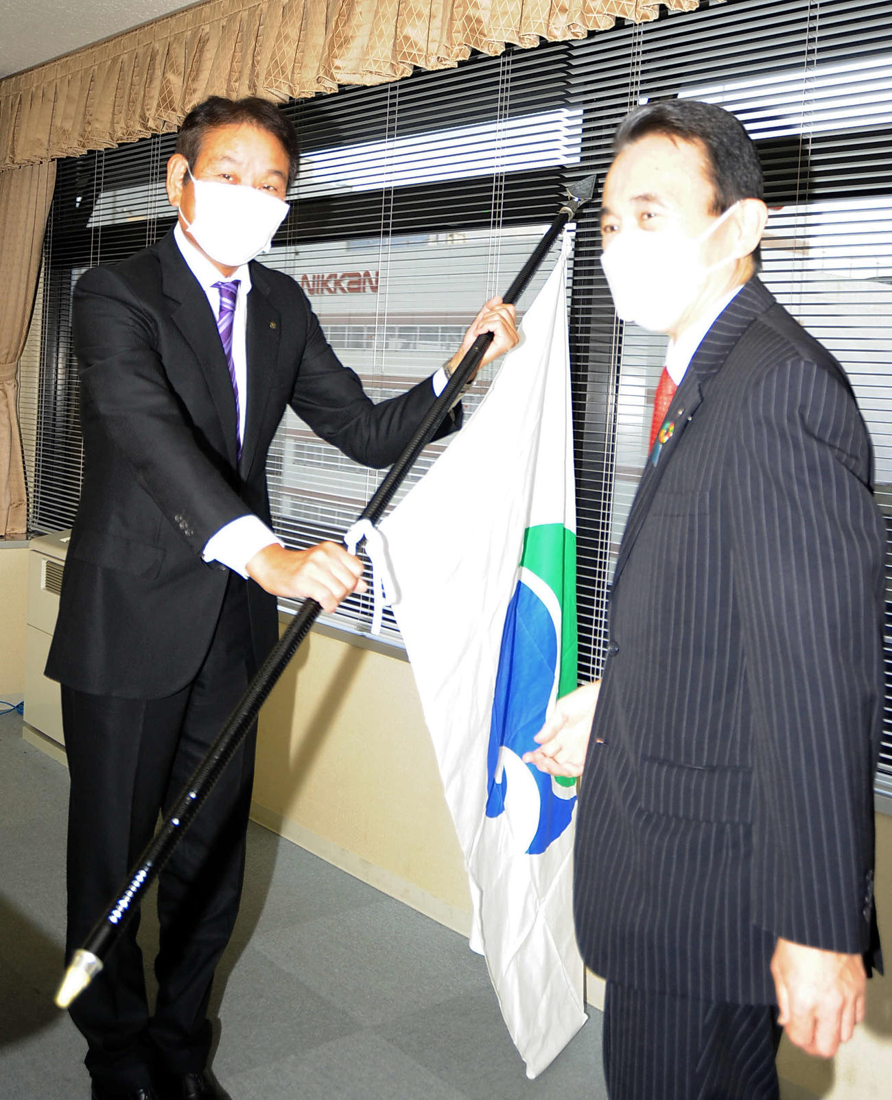鈴木浜松市長（右）から市旗を貸与されるヤマハの高井正人部長