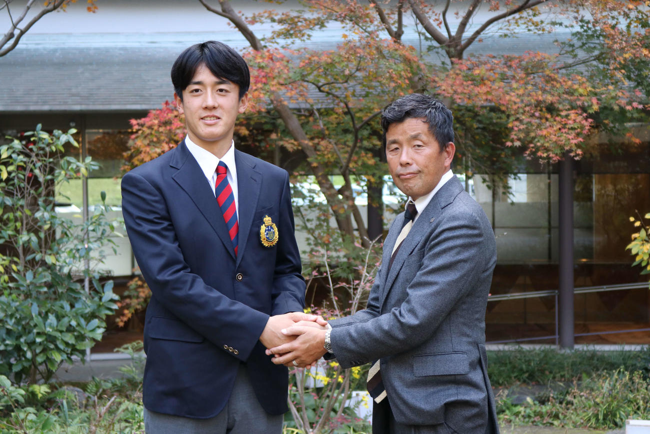仮契約を終えた京産大・北山（左）と握手する日本ハム熊崎担当スカウト（撮影・小林憲治）