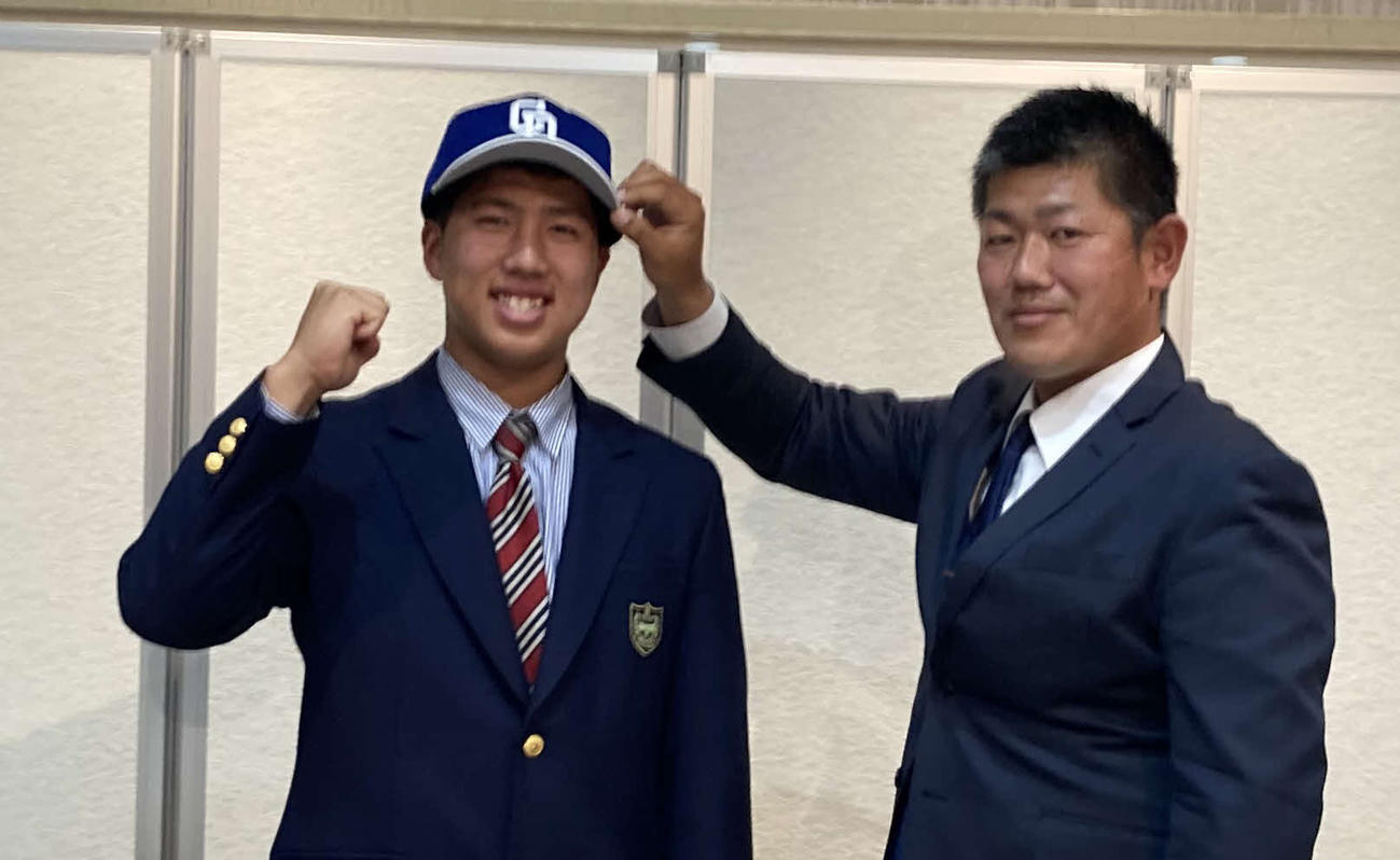 中日との仮契約を終えた豊橋中央・星野真生は、清水スカウトから帽子をかぶせてもらう（撮影・伊東大介）