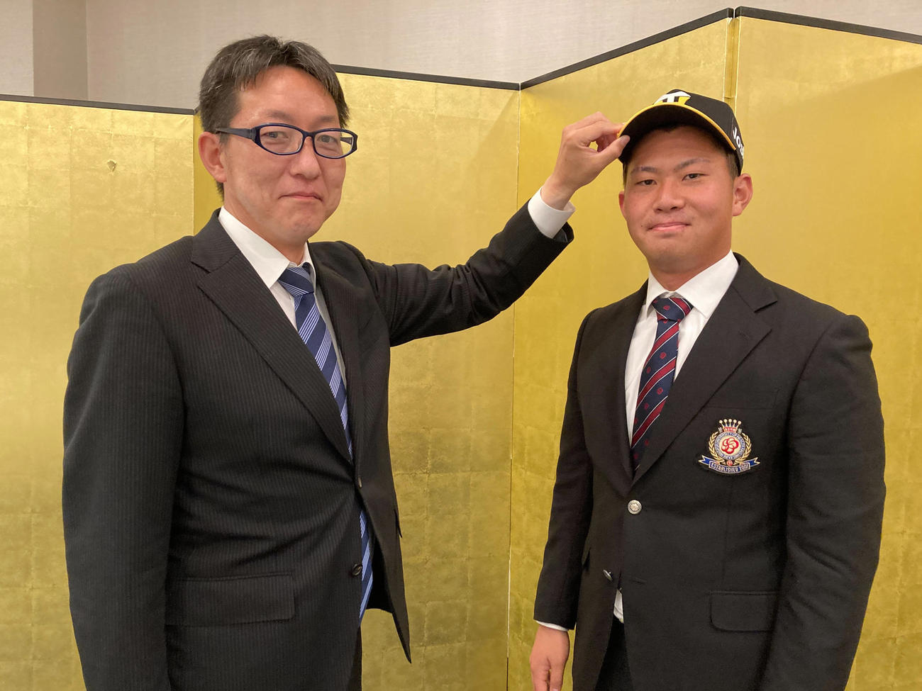 仮契約を結び笑顔をみせる阪神ドラフト3位の桐敷（右）、左は吉野スカウト（阪神球団提供）
