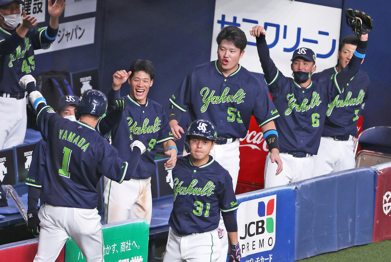 6回表ヤクルト1死一、二塁、中村の中前適時打で先制し、生還した山田（手前左）を笑顔で迎えるヤクルトナイン（撮影・前田充）