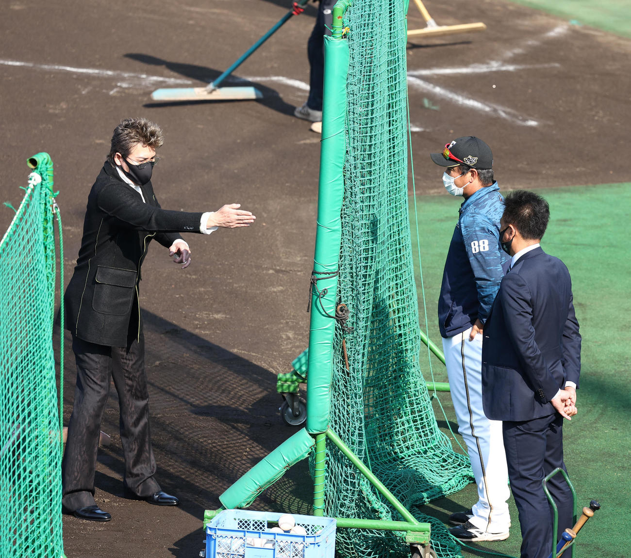 鎌ケ谷スタジアムを訪れ打撃練習用ネットを挟み言葉を交わす日本ハム新庄監督（左）と金子コーチ（中央）。右は林ヘッドコーチ（撮影・垰建太）
