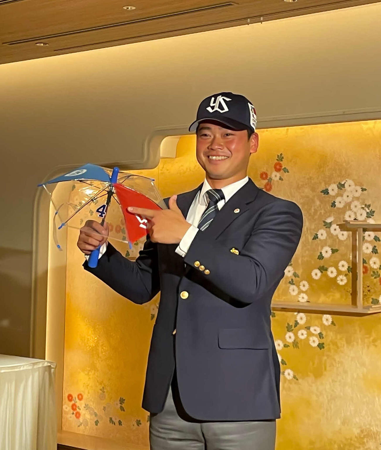 ヤクルトと仮契約を結び、背番号4の傘を手に笑顔の明大・丸山（撮影・保坂恭子）