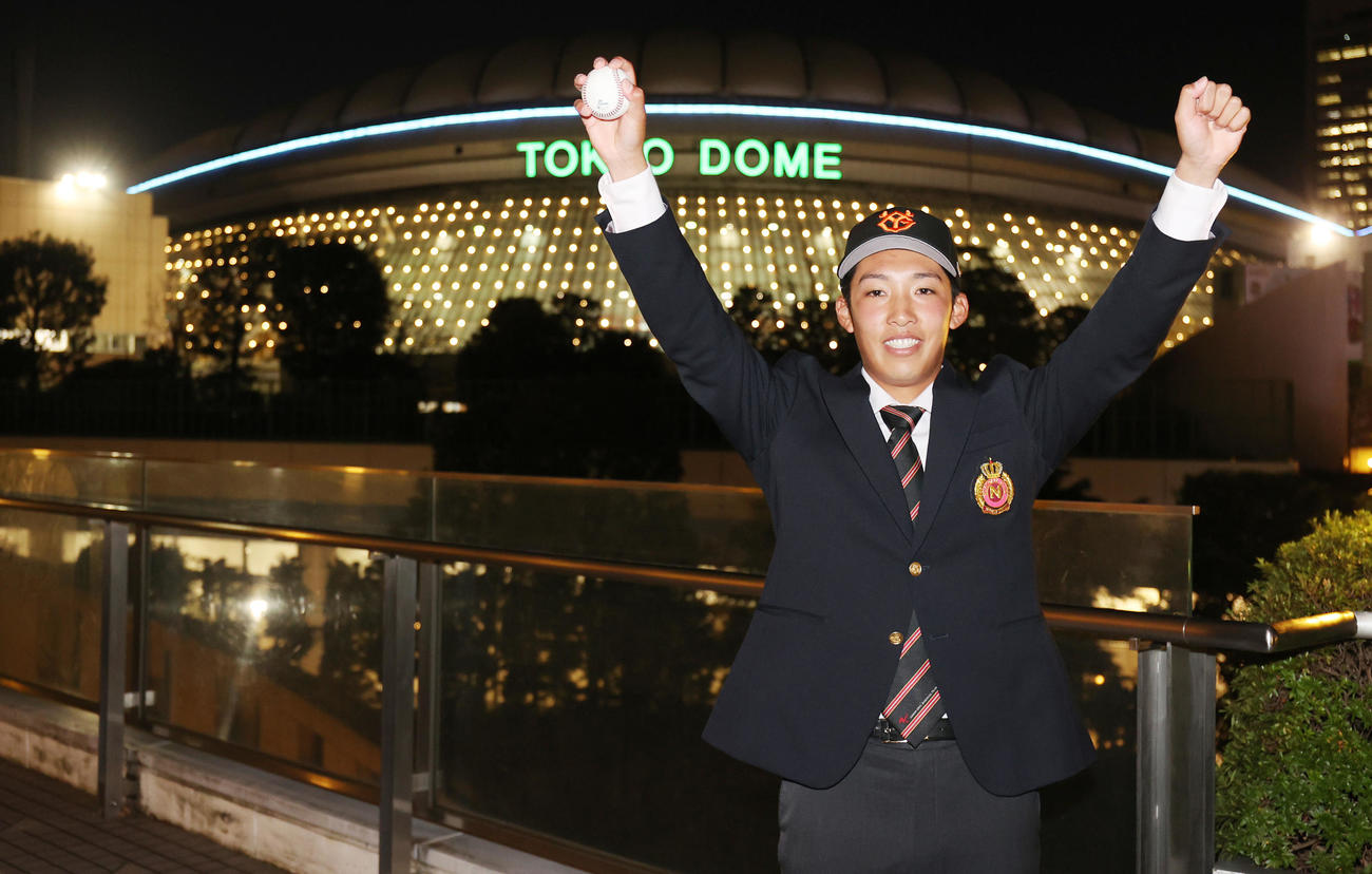 巨人3位指名の日大・赤星は仮契約を終え、日本シリーズ開催中の東京ドームを背に万歳（撮影・野上伸悟）