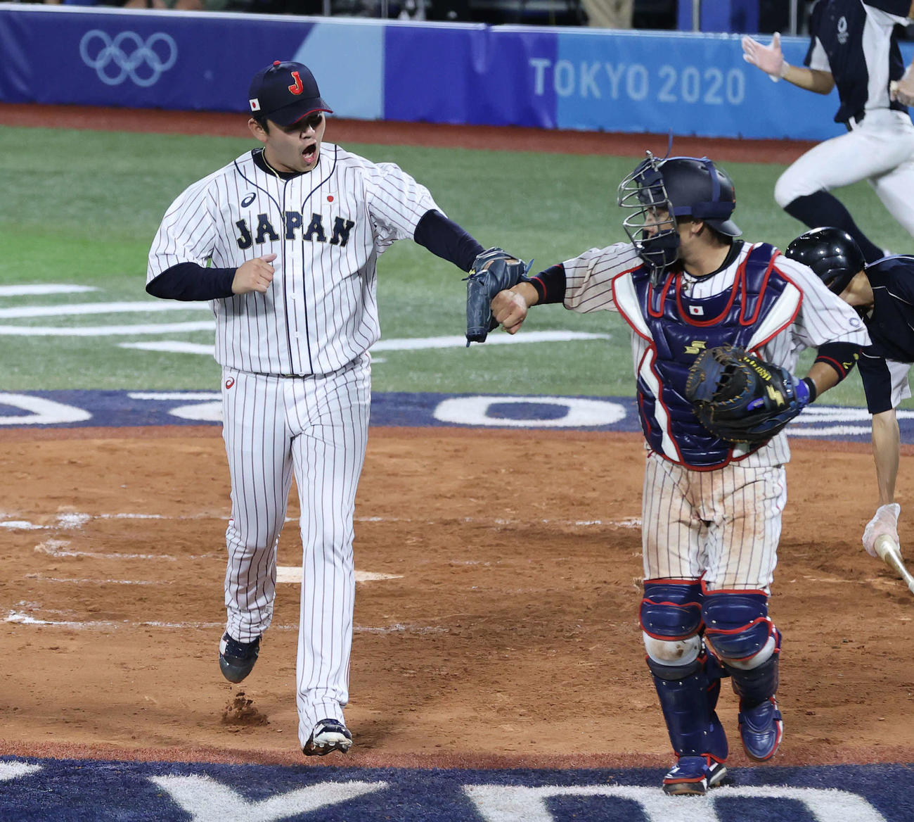 東京五輪の米国戦で山崎康晃（左）とタッチをかわす梅野隆太郎＝2021年8月2日