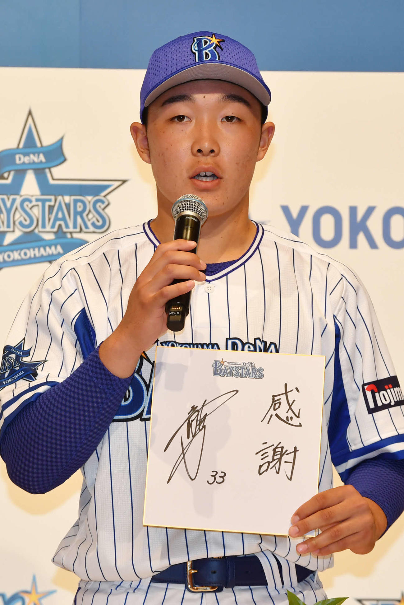 DeNA新入団選手発表会で色紙を手に抱負を語るドラフト3位の粟飯原（代表撮影）