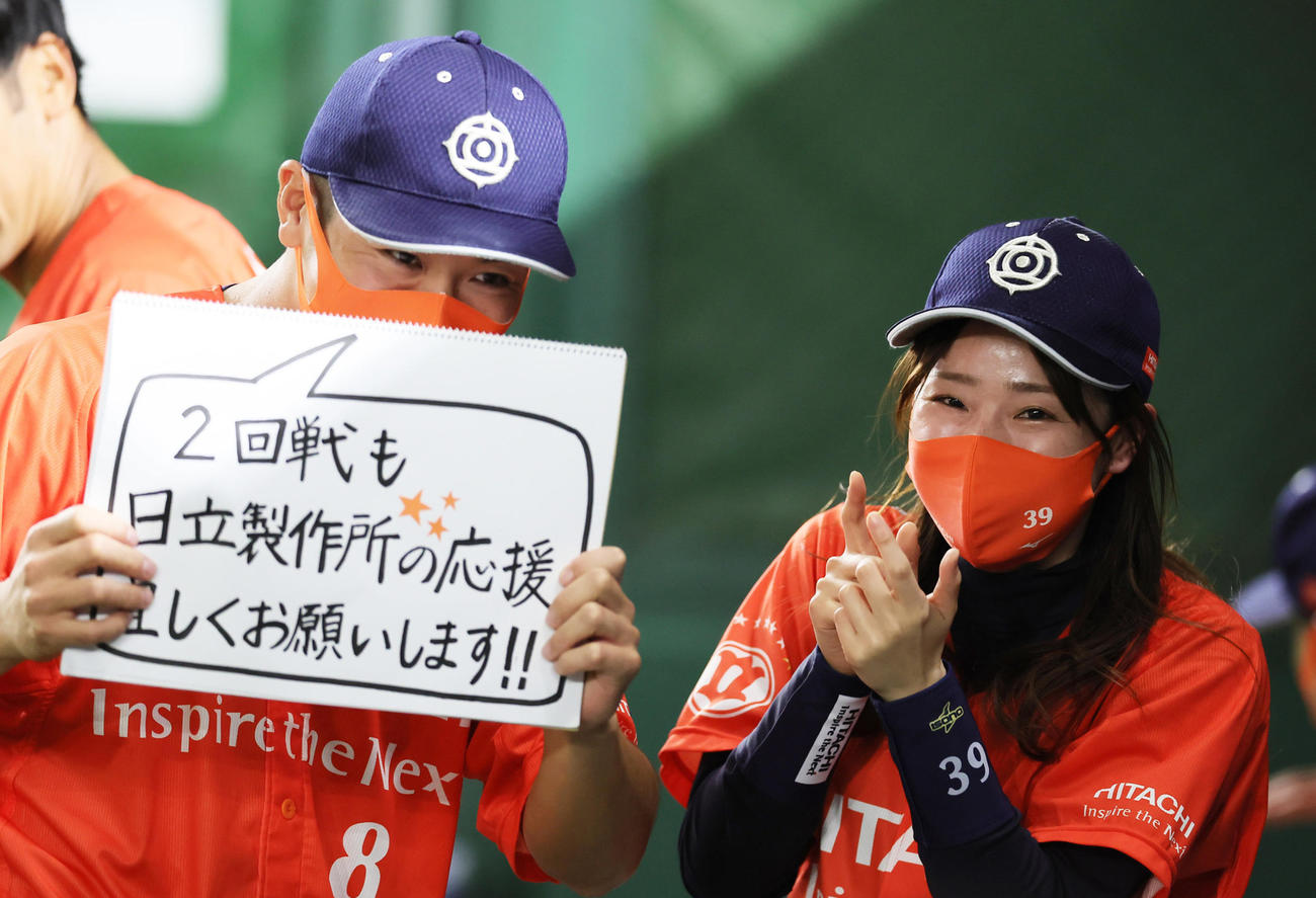 日立製作所チームマスコットの樋熊（右）に促され応援をお願いするメッセージを掲げる豊田（撮影・足立雅史）