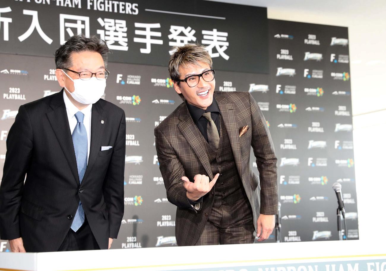 新入団選手発表会見で席に着くなりポーズをとる新庄監督。左は川村球団社長（撮影・黒川智章）