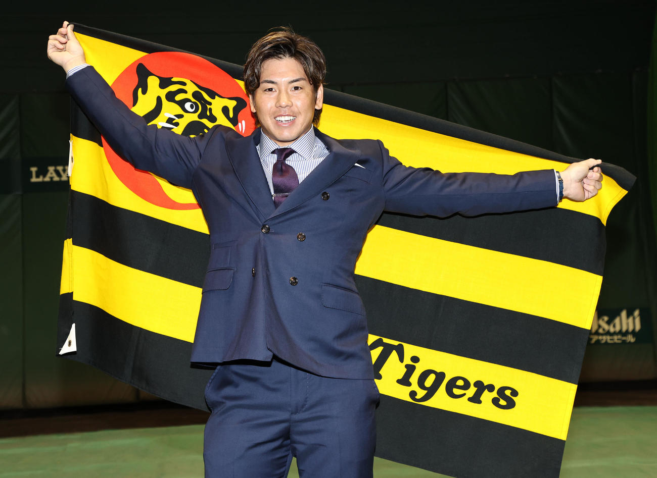新たに3年契約でサインし球団旗を背にポーズを決める阪神梅野隆太郎（撮影・加藤哉）