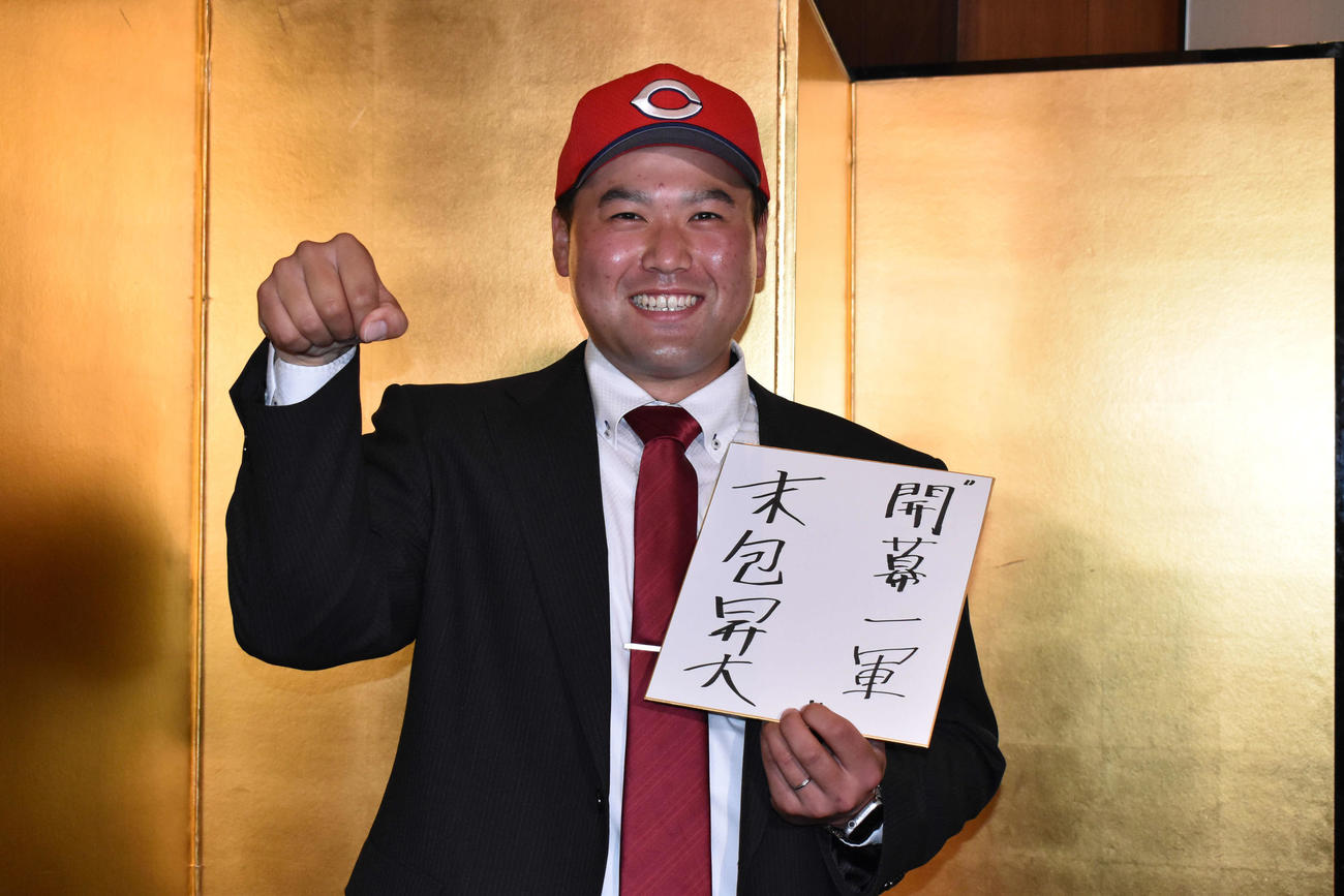 「開幕一軍」と記した色紙を左手に、右拳でコブラポーズを決める広島ドラフト6位の大阪ガス・末包（撮影・古財稜明）