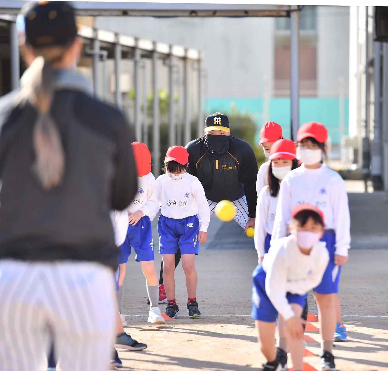 ゲストティーチャーとして小学校を訪れた佐藤輝（中央）は野球を体験する小学生を見守る（撮影・上田博志）