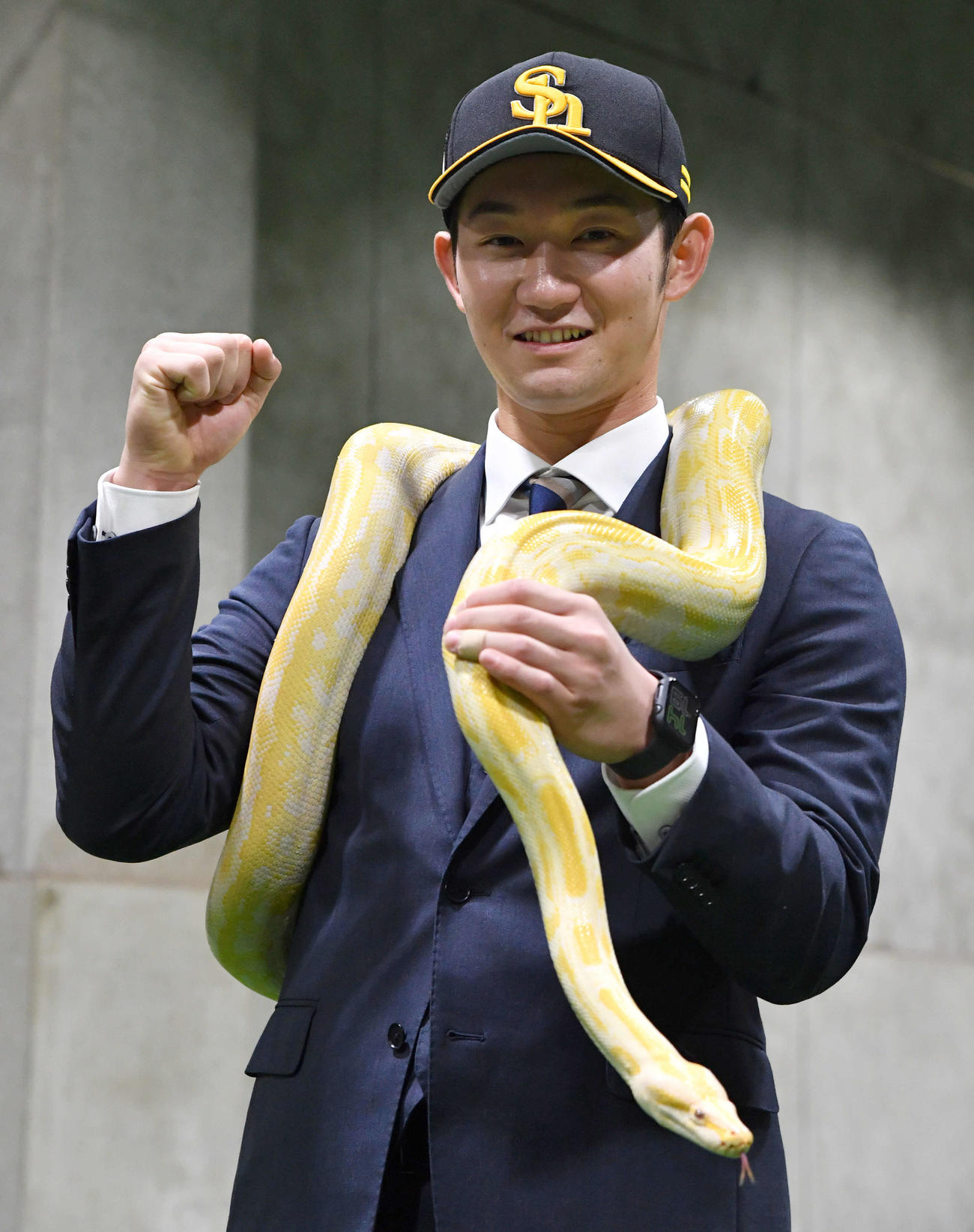 幸運を呼ぶとされるビルマニシキヘビを肩に巻き、ガッツポーズする正木（撮影・岩下翔太）