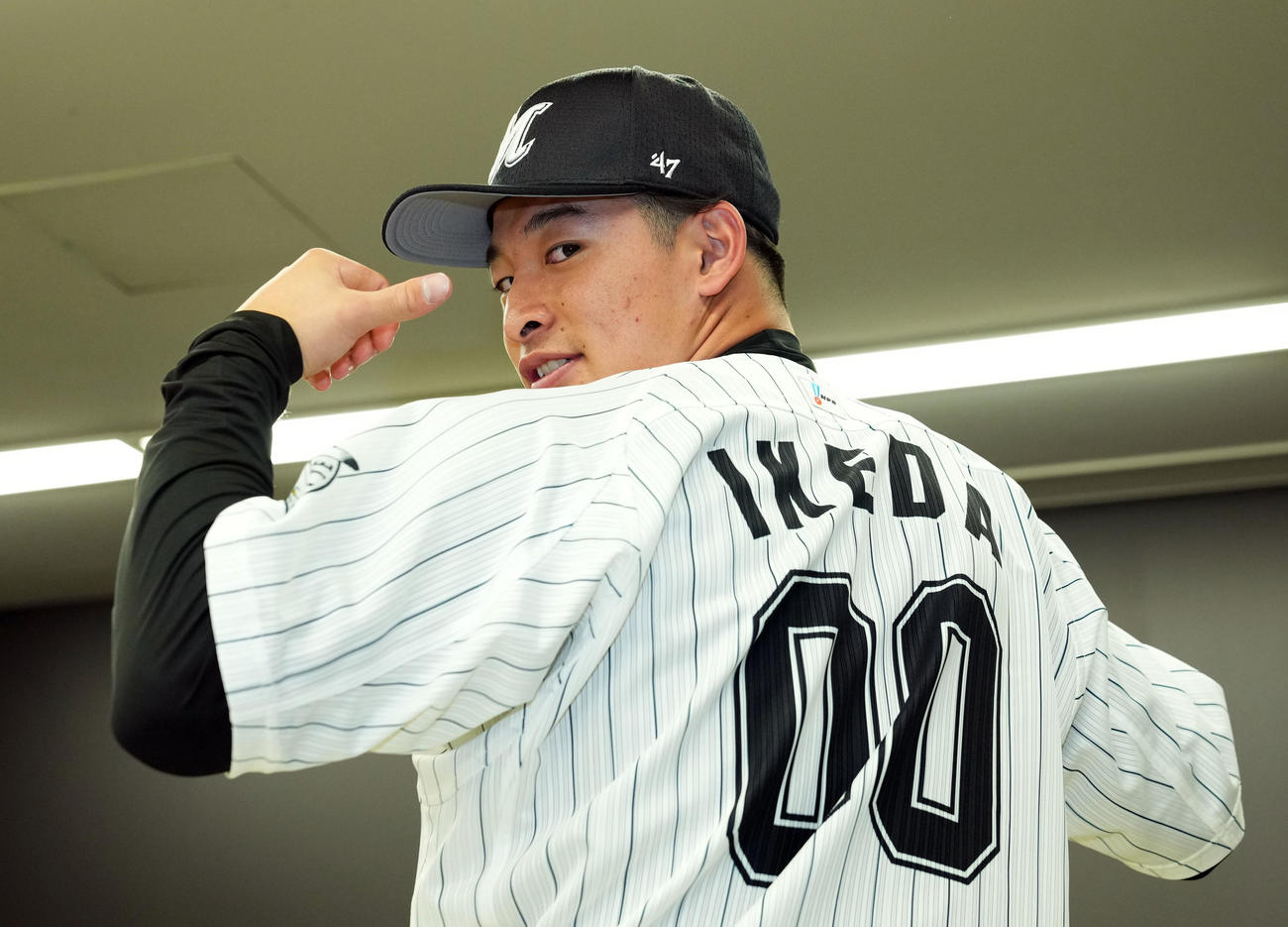 背番号00番を見せ笑顔を見せるロッテドラフト2位の国士舘大・池田（撮影・横山健太）