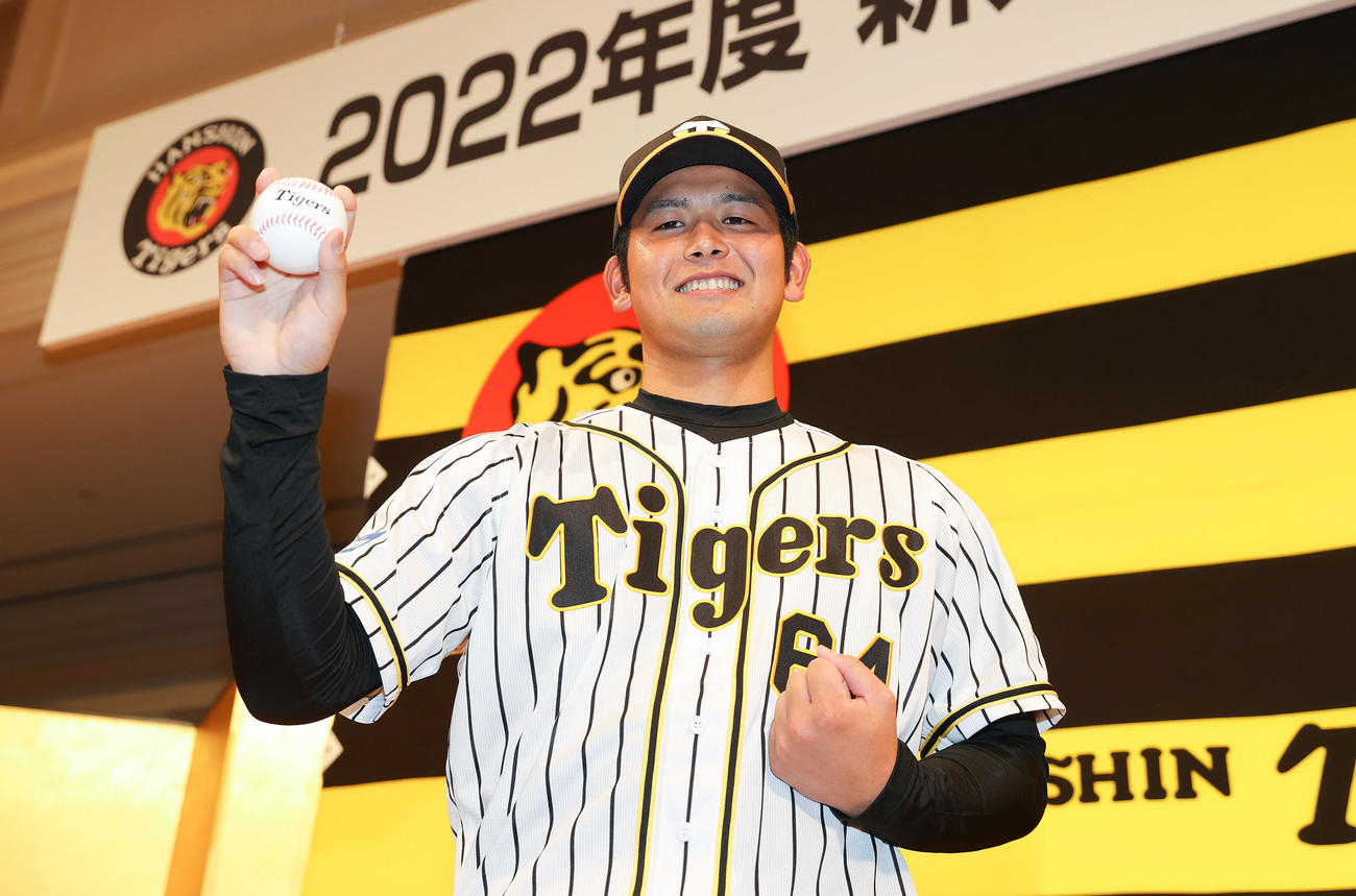 新人選手入団発表会で笑顔でポーズを決めるドラフト5巡目の阪神岡留（撮影・前田充）