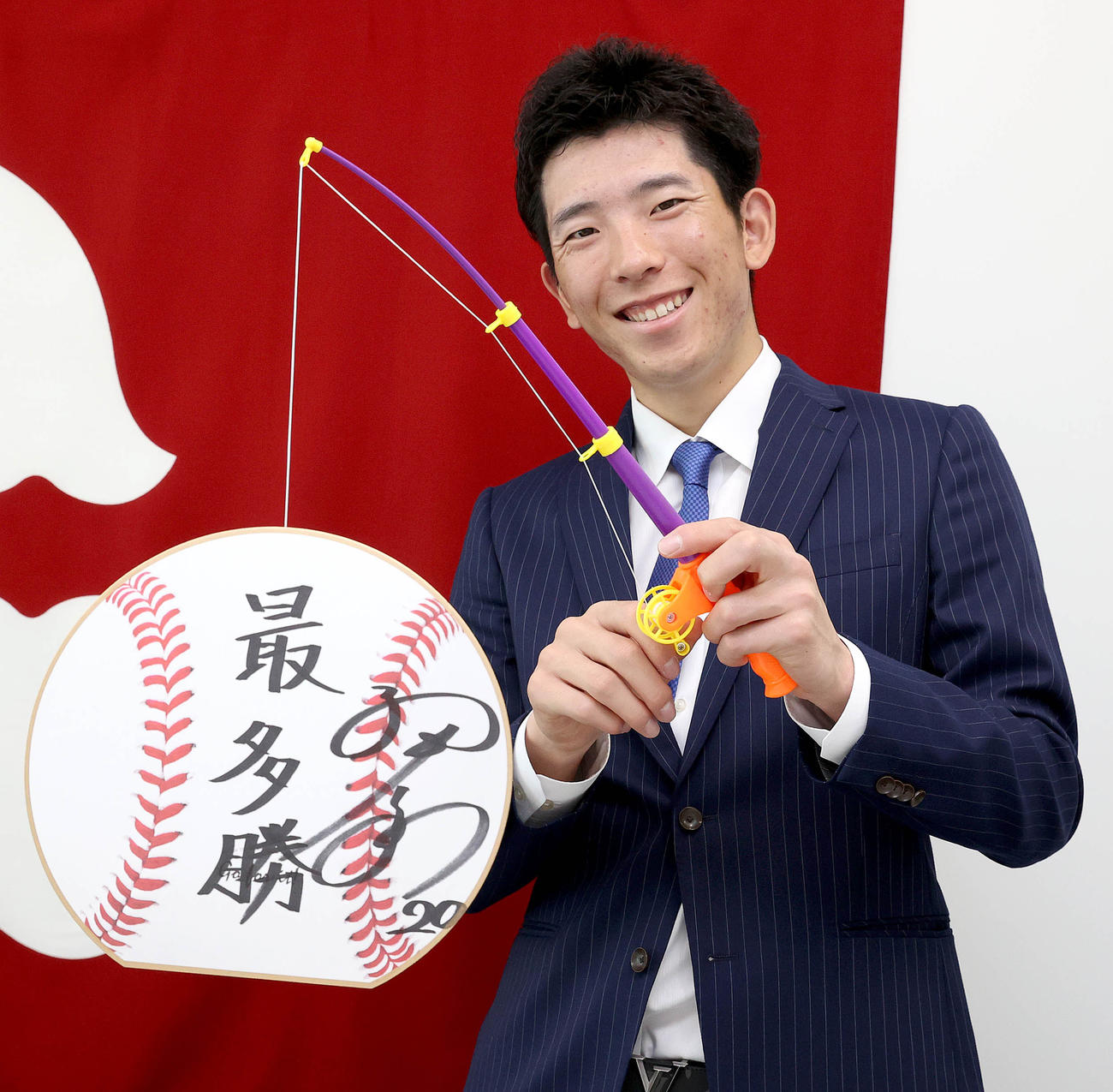 16日に都内の球団事務所で行われた契約更改後、「最多勝」と記した色紙を釣り上げる巨人戸郷（球団提供）