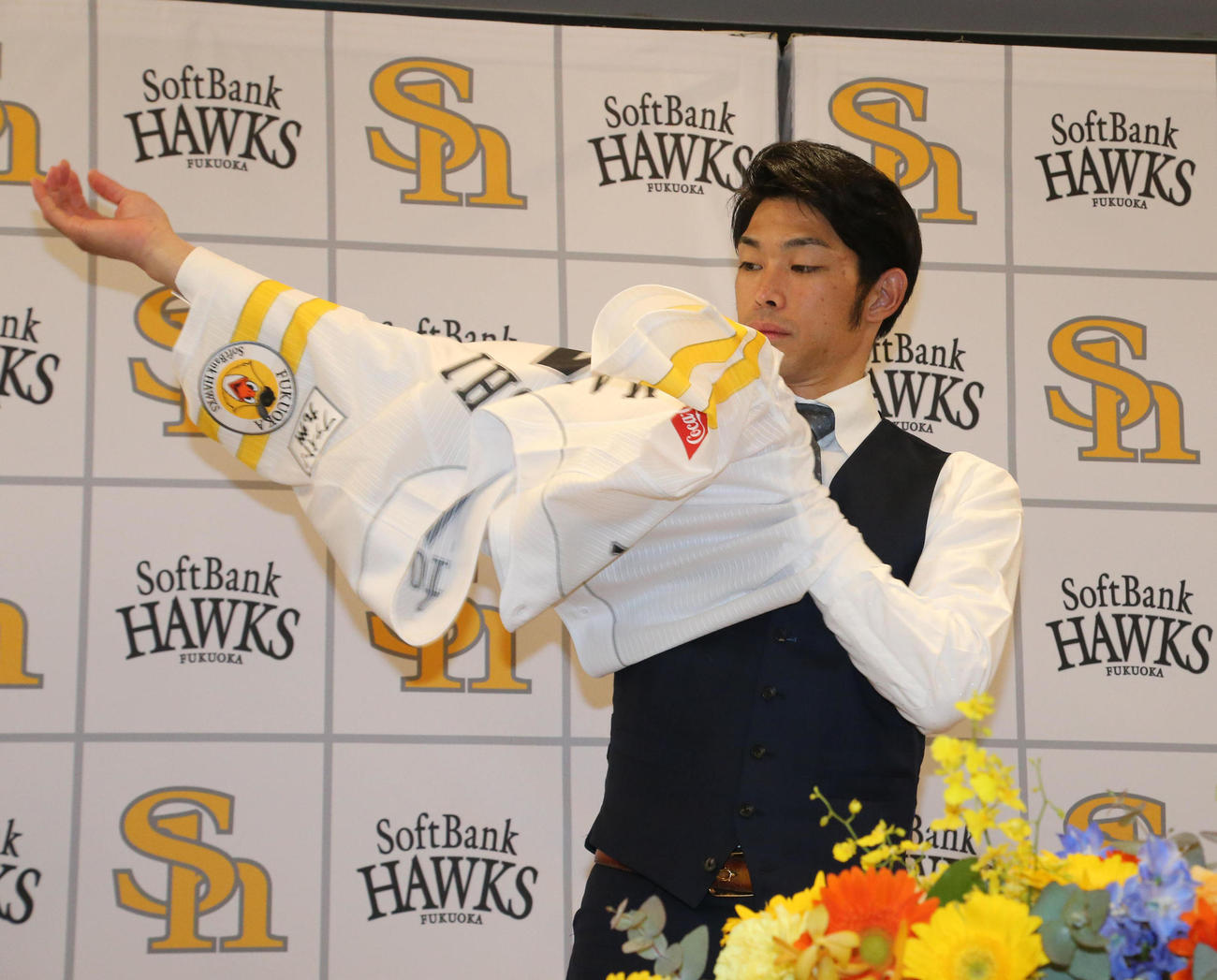 入団会見でユニホームにそでを通す又吉克樹（撮影・梅根麻紀）