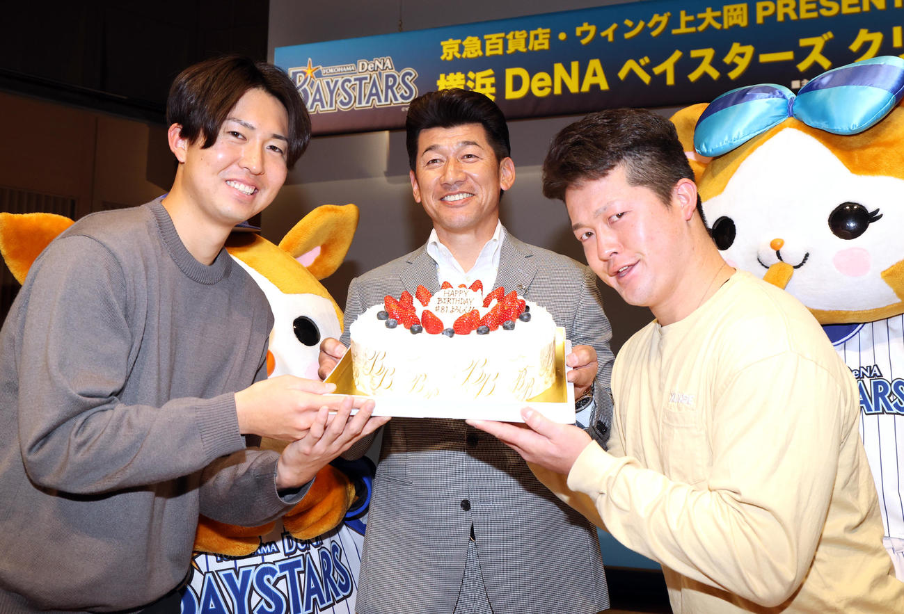 DeNAのクリスマストークショーで、25日に誕生日を迎える三浦監督（中央）はバースデーケーキをおどけた表情で持つ京山（左）と牧（右）に囲まれ、笑顔を見せる（撮影・浅見桂子）