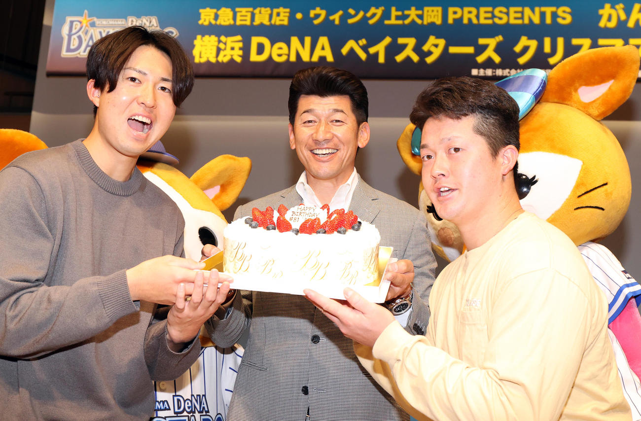DeNAのクリスマストークショーで、25日に誕生日を迎える三浦監督（中央）はバースデーケーキをおどけた表情で持つ京山（左）と牧（右）に囲まれ、笑顔を見せる（撮影・浅見桂子）