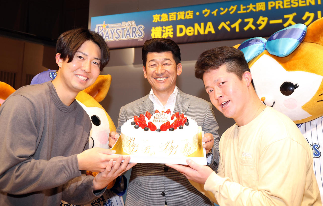 DeNAのクリスマストークショーで、25日に誕生日を迎える三浦監督（中央）はバースデーケーキをおどけた表情で持つ京山（左）と牧（右）に囲まれ、笑顔を見せる（撮影・浅見桂子）