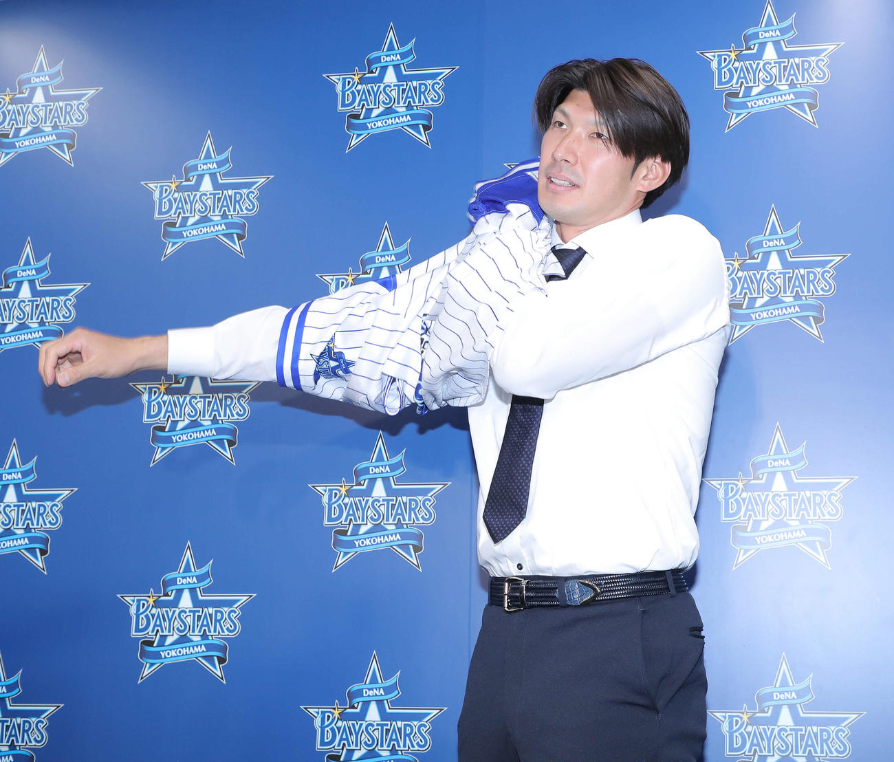 入団会見に臨み、ユニホームに袖を通すDeNA大田（撮影・河田真司）