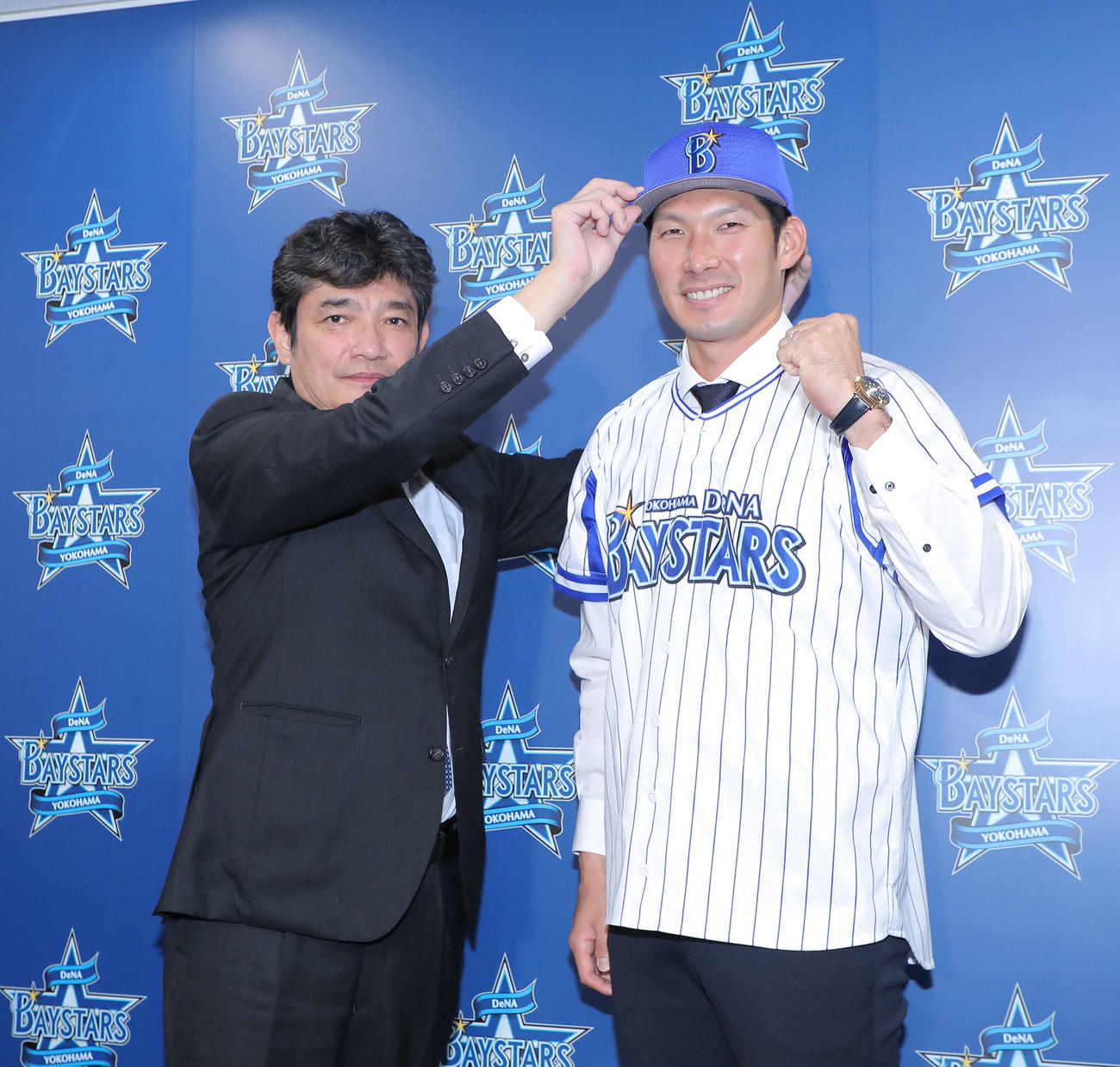 三原球団代表（左）に帽子をかぶせてもらい写真に納まるDeNA大田（撮影・河田真司）