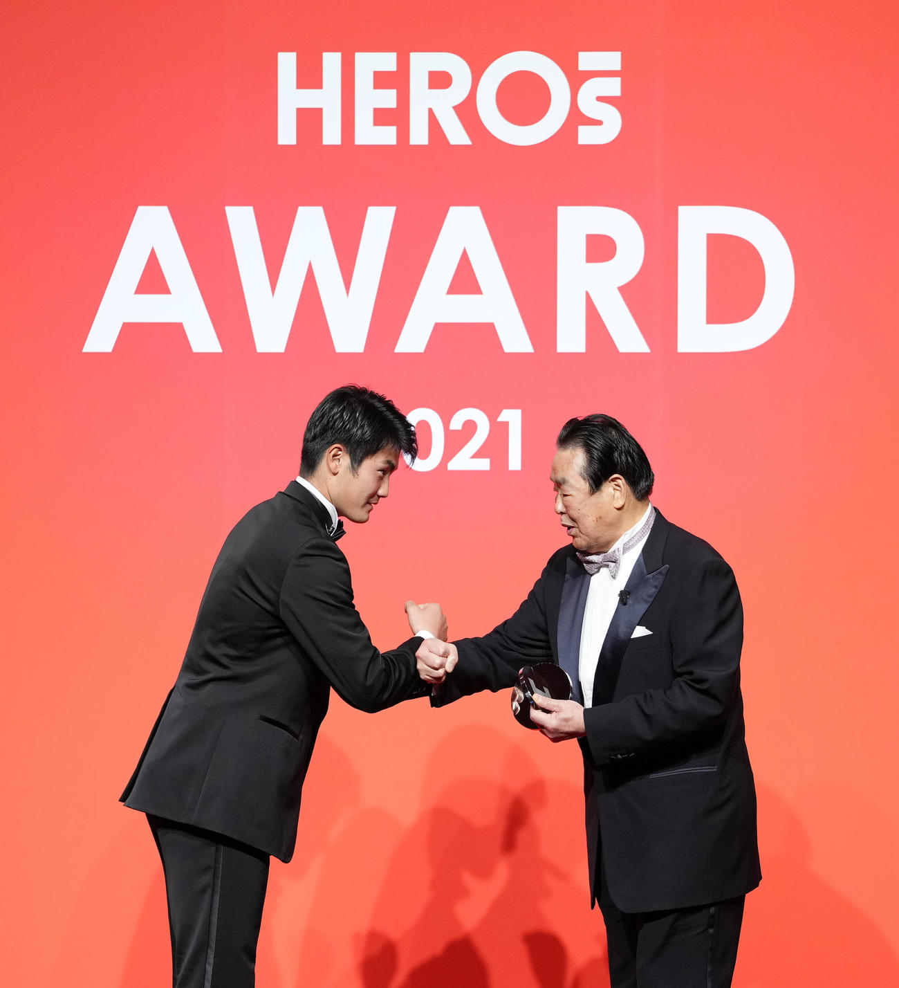 「HEROs AWARD 2021」を受賞し、プレゼンターを務める巨人菊地（左）から記念品を受け取り、タッチをする村田氏（撮影・菅敏）