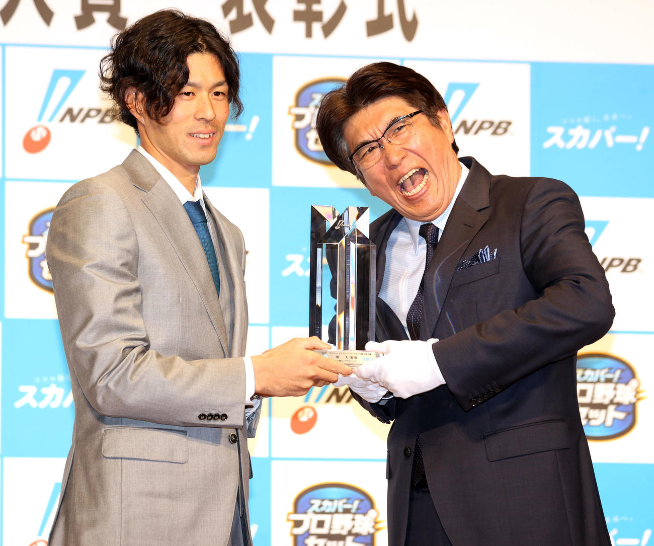 「2021スカパー！ドラマティック・サヨナラ賞　年間大賞表彰式」でプレゼンターの石橋貴明（右）からトロフィーを授与され笑顔を見せるロッテ岡大海（撮影・浅見桂子）