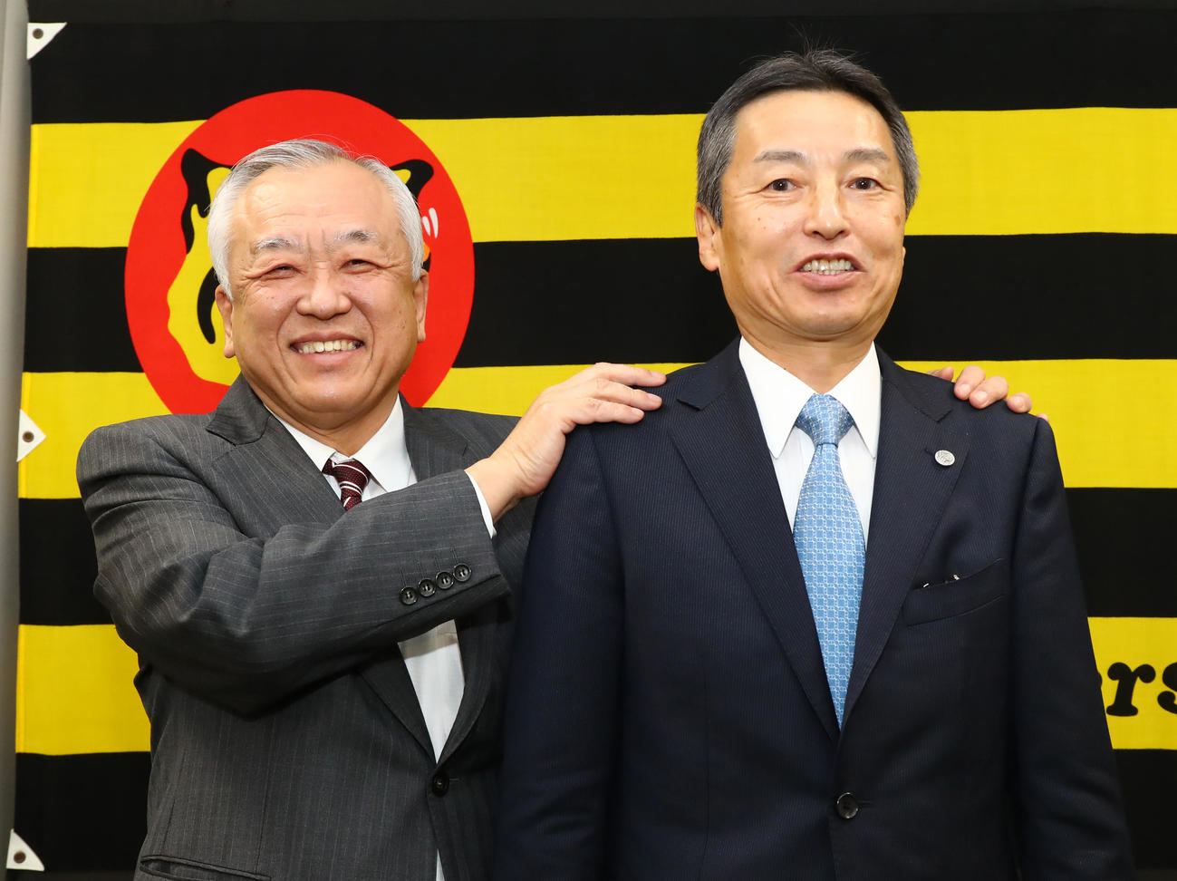 藤原オーナー兼球団社長（左）に肩をもまれる新たに代表取締役球団社長に就任する百北常務取締役（代表撮影）