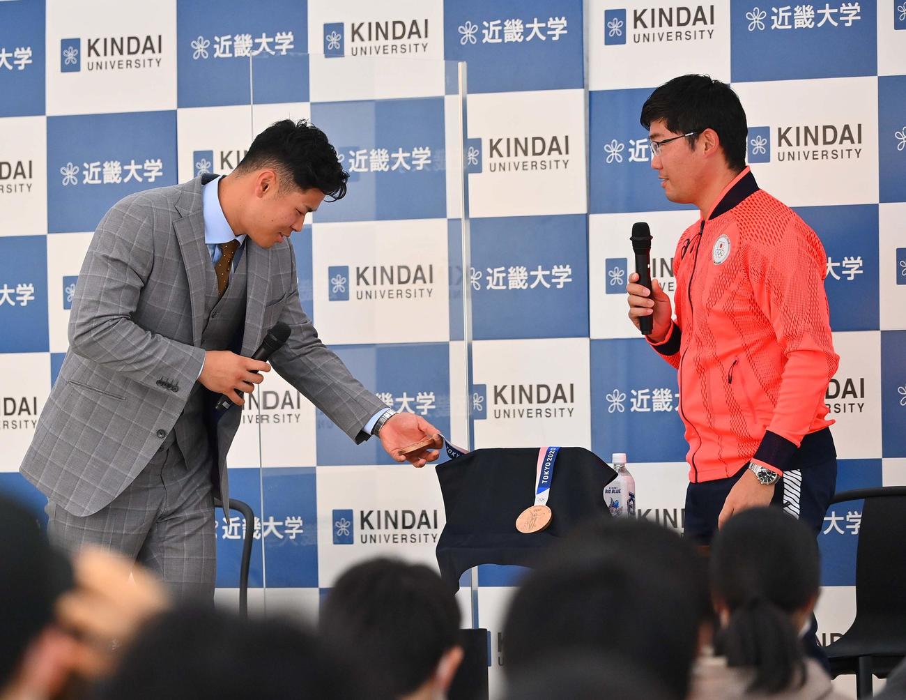 東京五輪アーチェーリー銅メダリスト古川（右）のメダルを触る阪神・佐藤輝（撮影・上田博志）